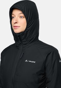 Zwarte geïsoleerde jas met een hoge kraag en capuchon, voorzien van een rits aan de voorkant en een logo op de borst; gladde textuur en een strak design.