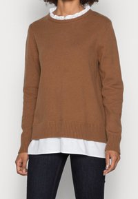 Brązowy sweter dziany z prążkowanym dołem i mankietami, nałożony na białą koszulę z kołnierzykiem, prezentowany na neutralnym tle.