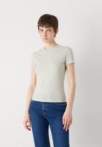 Ljusgrön t-shirt med kort ärm i mjukt material, figursydd design med rund halsringning och liten logotypdetalj på bröstet. Kombinerad med blå jeans.