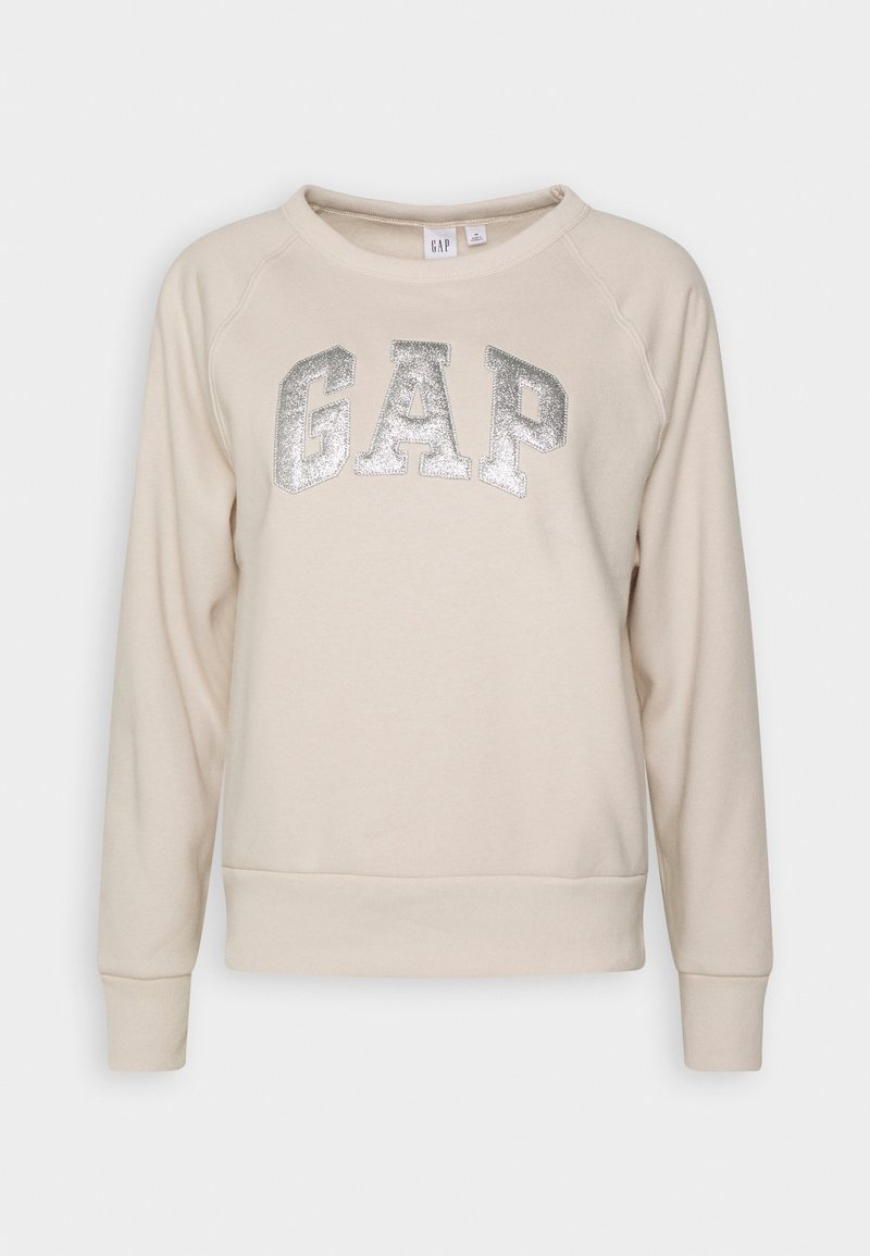 Sweat-shirt à manches longues couleur crème avec logo « GAP » pailleté argenté sur la poitrine, col rond, poignets et ourlet côtelés.
