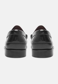 Scarpe in pelle nera con finitura lucida, dotate di tacco basso e punta rotonda, cuciture visibili e un logo discreto sul tacco.