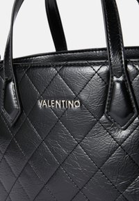 Bolsa de mão de couro preto acolchoado com logótipo prateado "Valentino", apresentando alças duplas e textura lisa com padrão de diamante.