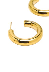 Złote kolczyki w kształcie obręczy z polerowanym, zaokrąglonym wzorem o grubym, zakrzywionym kształcie i bezpiecznym zapięciu na sztyft.