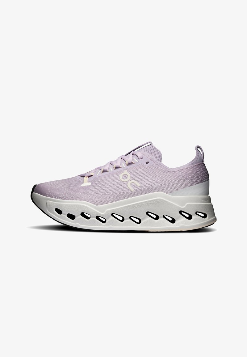 Chaussure de sport violet clair avec semelle blanche, présentant des découpes ovales noires et une languette au talon, logo latéral visible sur la tige en maille.