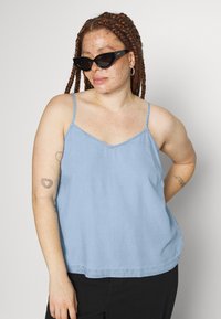 Top azul claro, sem mangas, com alças ajustáveis e decote em V. Feito de um tecido suave com um corte descontraído e uma barra que curva ligeiramente para cima.
