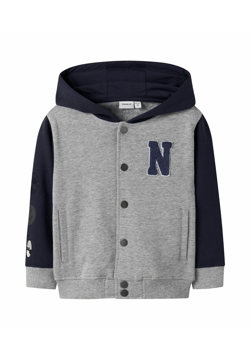 Grå sweatshirtjacka med en marinblå huva, tryckknappsstängning och marinblå ärmar med design av smileys och fotbollar. "N"-patch på framsidan.