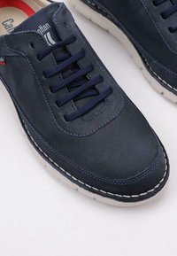 Zapato de piel navy con cordones azules y suela blanca. Presenta una puntera redonda y costuras en contraste. El interior tiene un acento rojo.