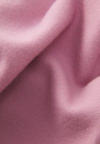 Měkká, světlá mauve pletenina s viditelnou jemnou texturou a jemnými záhyby vytvářejícími stíny a odlesky.