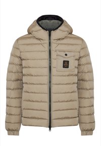 Giacca puffa beige con cappuccio, design a trapuntatura orizzontale, chiusura frontale con zip e tasca sul petto con un patch logo. Texture liscia.