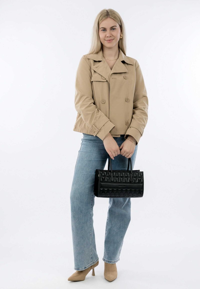 Beige cropped jacket with double-breasted buttons, paired with light blue straight-leg jeans. Holding a black quilted handbag, wearing beige heels.
