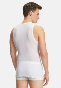 Top senza maniche bianco realizzato in un tessuto morbido ed elastico con una trama a costine e un design aderente, visto da dietro.