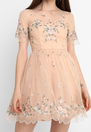 Brzoskwiniowa sukienka z krótkim rękawem z przezroczystą warstwą, haftem kwiatowym na gorsecie, rękawach i dole, dopasowaną talią oraz falistymi krawędziami.
