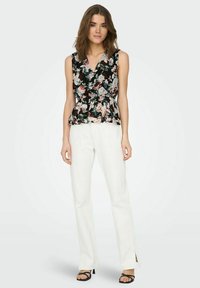 Top sin mangas negro con estampado floral y cintura peplum, con flores rosas y verdes y un escote profundo, combinado con pantalones anchos blancos.