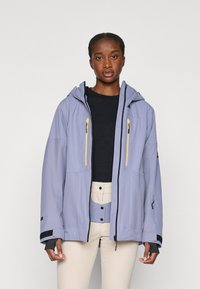 Vaaleanlila vedenpitävä takki hupulla, jossa on keltaiset vetoketjut, kaksi etutaskua ja mustat yksityiskohdat hihansuissa ja sivuilla.