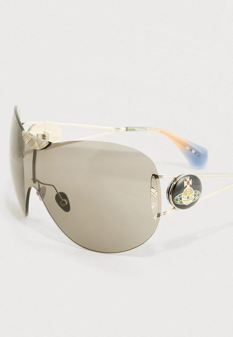 Sonnenbrille mit großen grauen Gläsern, dünnen goldenen Metallrahmen, strukturierten silbernen Akzenten und einem dekorativen Logo an einem Bügel. Blau-orangefarbene Enden.