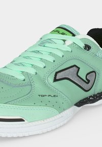 Αθλητικό παπούτσι ανοιχτού πράσινου χρώματος με κορδόνια μέντας, ασπρόμαυρη σόλα, με σήμανση "TOP-FLEX" και μεγάλο στυλιζαρισμένο λογότυπο "J" στο πλάι.