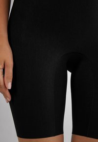 Zwarte high-waisted fietsbroekjes van gladde stof, met een strakke pasvorm, zichtbare stiksels en een afgeronde snit bij het bovenbeen.