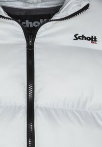 Biała puchowa kurtka z czarnym zamkiem, z wysokim kołnierzem. Na górze po lewej stronie znajduje się czarne logo "Schott NYC". Gładka tekstura.