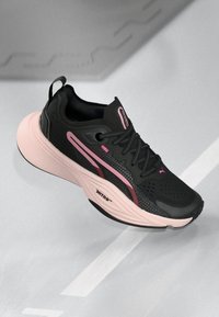 Czarne buty sportowe z różowymi akcentami, charakteryzujące się teksturowanym wierzchem, oddychającą siateczką, grubą, amortyzującą podeszwą oraz odblaskowymi detalami.