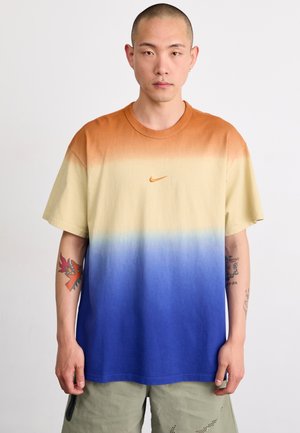 T-shirt Nike présentant un dégradé allant de l'orange à la crème puis au bleu, en matériau coton, à manches courtes, col rond et petit logo sur la poitrine.