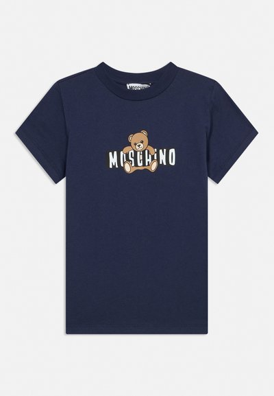 T-shirt bleu marine à manches courtes avec un ours en peluche marron et un texte blanc en gras « MOSCHINO » sur la poitrine.