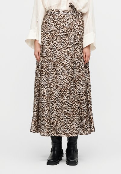 Μακριά φούστα με λεοπάρ animal print σε ανοιχτό καφέ και μπεζ, με δέσιμο στη μέση και ρέον ύφασμα με στρώσεις. Μαύρα μποτάκια μέχρι τον αστράγαλο ολοκληρώνουν το σύνολο.