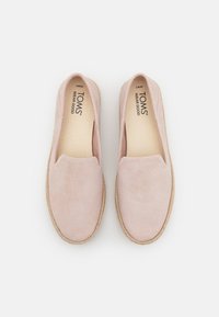 Blush pink slip-on shoes made of soft suede with a jute rope sole. The insole features "TOMS WEAR GOOD" branding. Smooth, rounded shape.