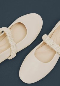 Kermavaaleat ballerinat pehmeällä kärjellä ja kerätystä elastisesta nauhasta. Sujuva nahkamainen pinta, minimalistikko muotoilu.