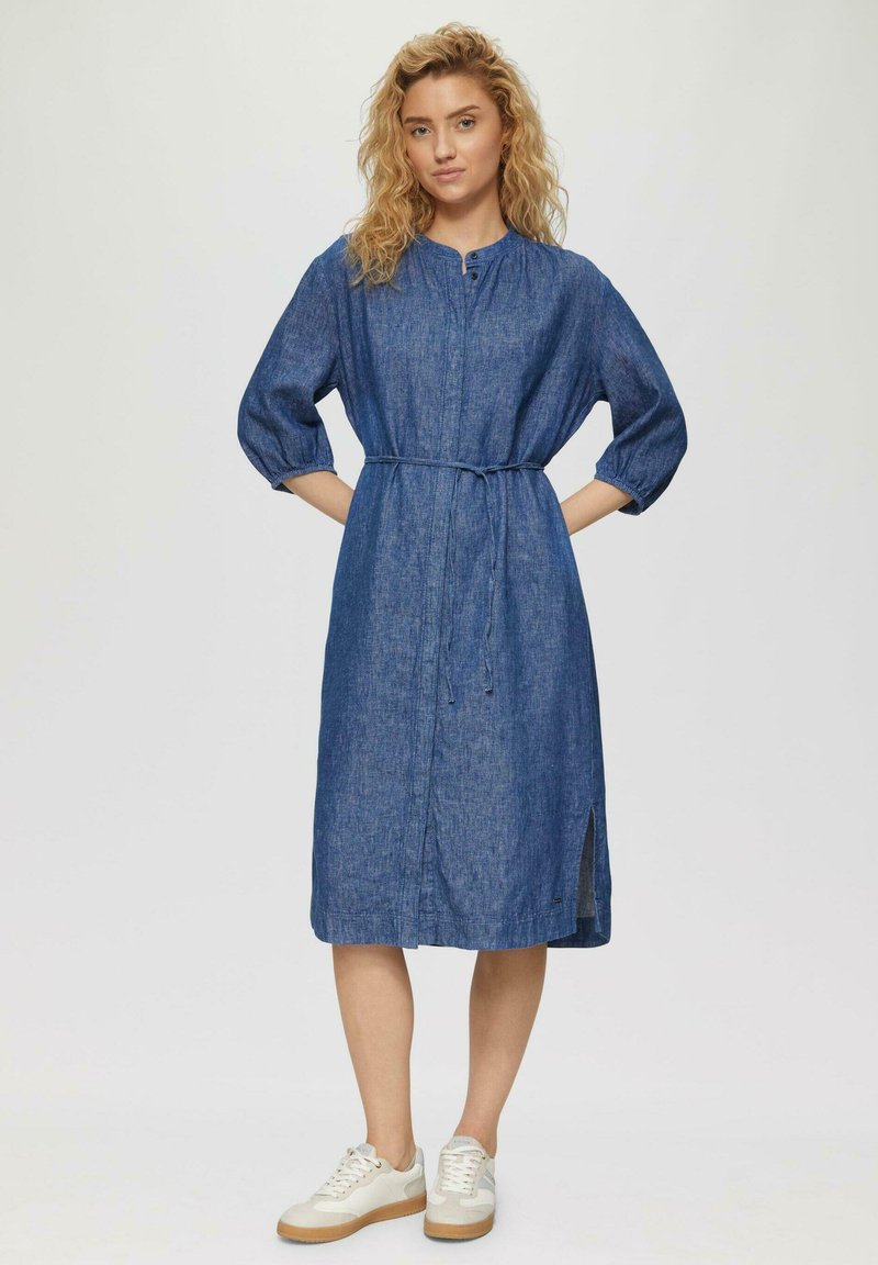 Denimkleid mit lockerem Schnitt, halben Ärmeln, Knopfverschluss und einem Bindegürtel in der Taille; verfügt über seitliche Schlitze und einen blauen strukturierten Stoff.