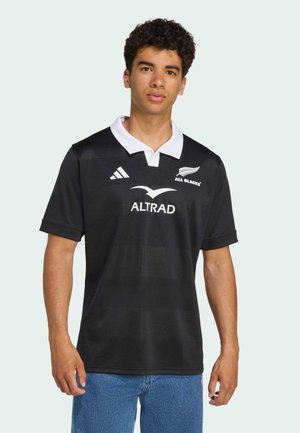 Maillot de rugby noir avec un col blanc, présentant un design texturé, le logo "All Blacks" et le logo du sponsor "ALTRAD" sur le devant.