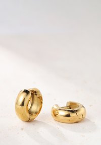 Goldene Creolen mit einer glatten, glänzenden Oberfläche. Abgerundetes Design mit einem geteilten Detail und einem kleinen Loch für eine sichere Befestigung.
