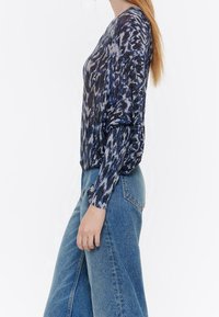 Blauw en zwart geblokte trui met lange mouwen en een slim fit, gemaakt van een glanzende, gestructureerde stof, gecombineerd met high-waisted denim.