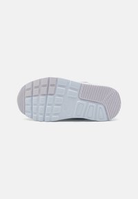 Semelle d'extérieur de chaussure de sport gris clair avec un caoutchouc texturé, des crampons carrés et rectangulaires pour l'adhérence, et un logo Nike en relief.