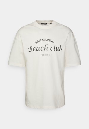Kremowa koszulka z krótkim rękawem i okrągłym dekoltem, z napisem "SAN MARINO Beach club" w wyraźnym czarnym foncie. Luźny krój, wykonana z bawełny.