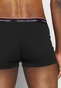 Svarte bomullsboxere med Tommy Hilfiger-logo på midjebåndet, som har røde og hvite detaljer. Myk, tettsittende design med en jevn tekstur.