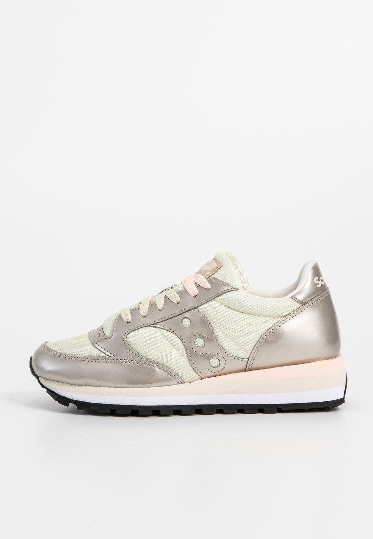 Zapatilla ligera en crema y plata. Presenta un upper de tejido con acentos metálicos, cordones y un detalle rosa en contraste en la suela.