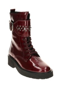 Burgundy patent leather ankle boot with a rounded toe, lace-up front, buckle accent, and metallic studs along the strap. Thick black sole.
