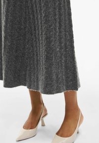 Grijze geribbelde gebreide rok met een rafelige onderrand; gecombineerd met lichtbeige slingback hakken met een spitse neus en een bescheiden hak.