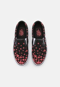 Czarne płócienne buty wsuwane z wzorem małych czerwonych serc, białe gumowe podeszwy oraz czarna wkładka z detalem logo.