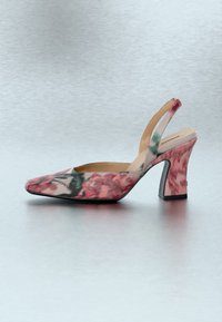 Ροζ και πράσινο γυναικείο παπούτσι με λουράκι στο πίσω μέρος, ψηλό τακούνι με ανθισμένο σχέδιο, μυτερή μύτη και φαρδύ χοντρό τακούνι πάνω σε ανοιχτό γκρι επιφάνεια.