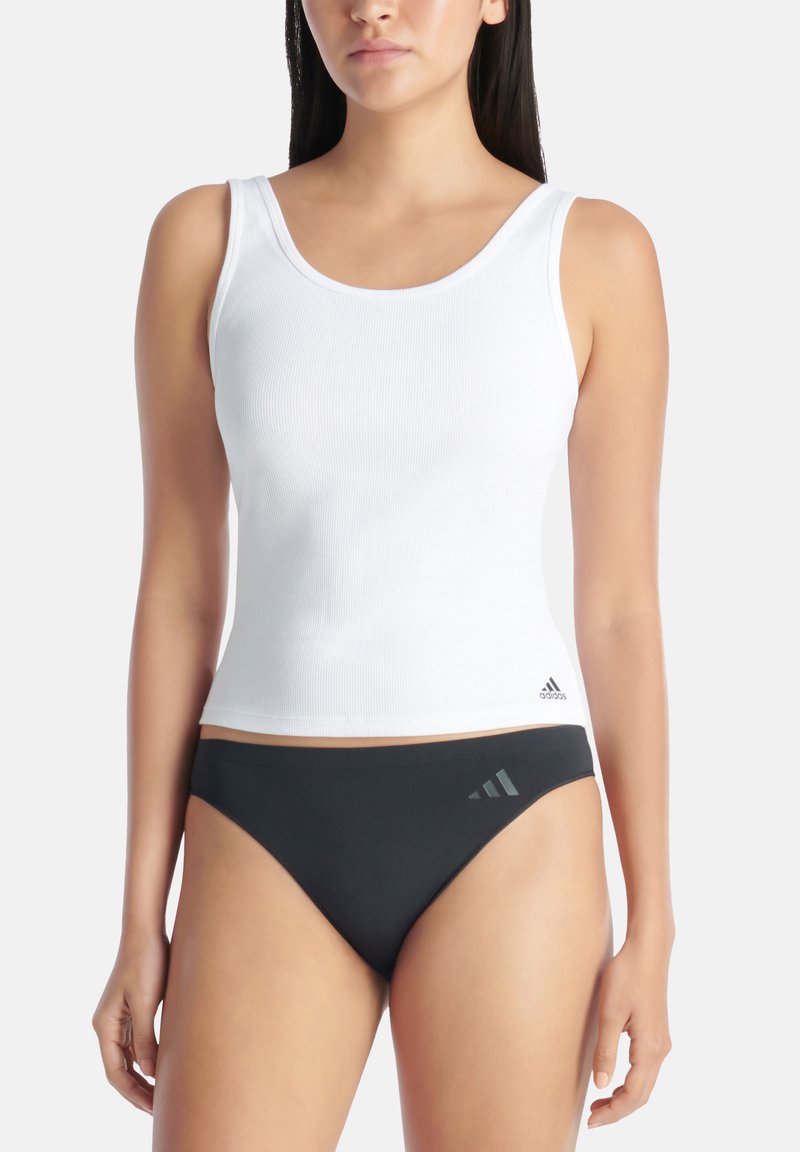 Biała ribbed top bez rękawów z szerokimi ramiączkami, ozdobiona małym czarnym logo Adidasa, w zestawieniu z czarnym dołem bikini z detalami w postaci trzech pasków.