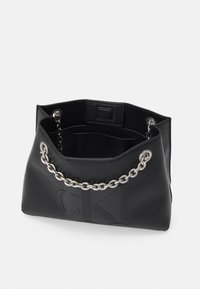 Sac à main en cuir noir avec une poignée en chaîne argentée, présentant une texture lisse et un logo embossé à l'avant. Design à ouverture supérieure.