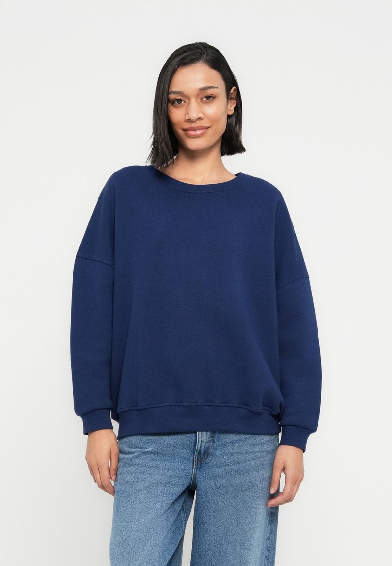 Marineblauer Pullover mit Rundhalsausschnitt, oversized Passform und langen Ärmeln. Hergestellt aus weichem Stoff, verfügt er über gerippte Bündchen und Saum.