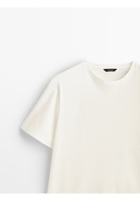 T-shirt en coton blanc à manches courtes avec un col rond et une étiquette noire visible sur fond blanc.