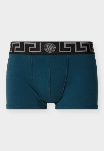 Γαλάζια ανδρικά μποξεράκια με μαύρη ελαστική μέση, διακοσμημένη με ασημένιο μοτίβο ελληνικού κλειδιού και έμβλημα με το κεφάλι της Μέδουσας στο κέντρο μπροστά.