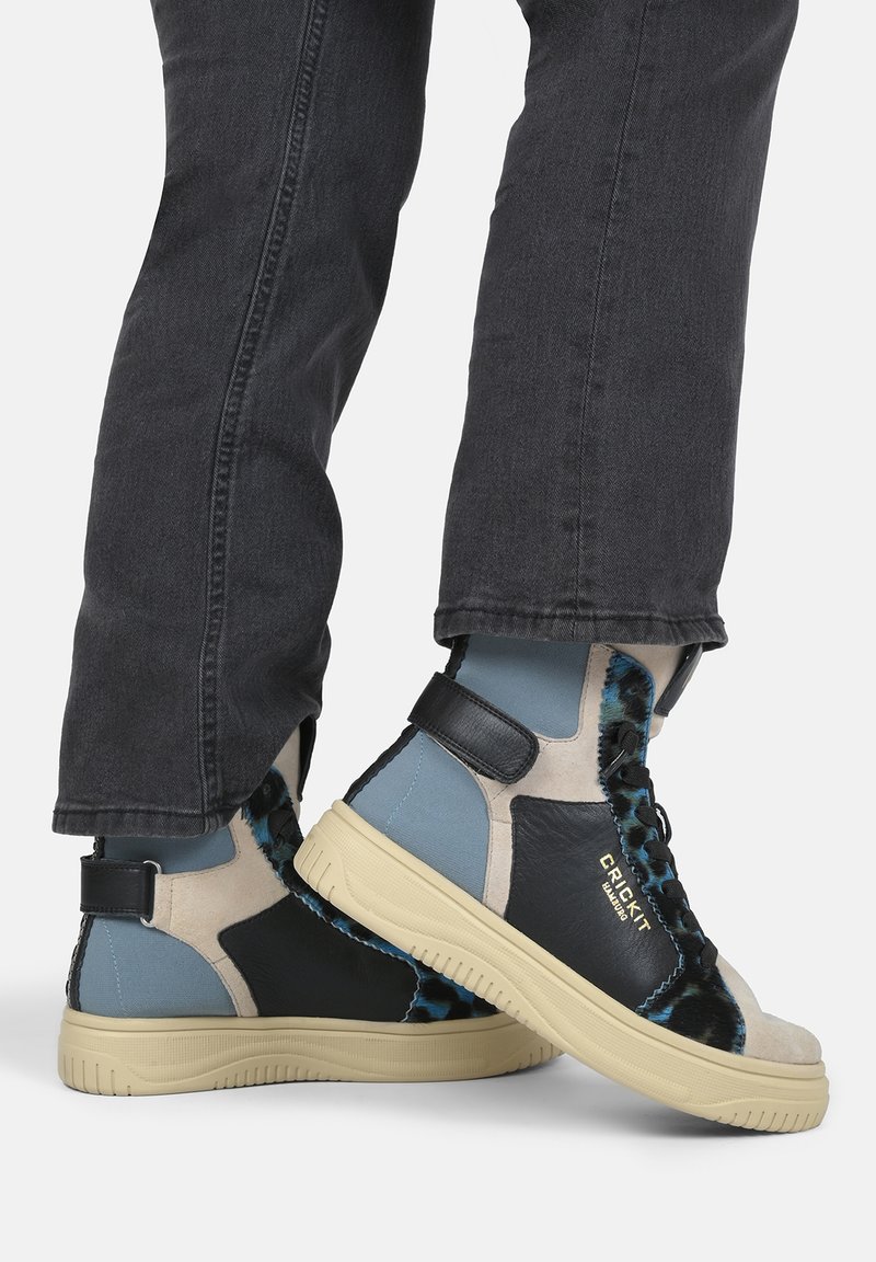 Sneakers alte in grigio, blu e nero, realizzati con materiali tessili e in pelle, caratterizzati da una suola in gomma di colore chiaro e una cinghia per la caviglia regolabile.