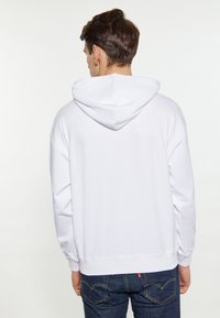 Witte hoodie met een relaxed fit, lange mouwen en ribgebreide manchetten. Heeft een kangoeroezak en stikseldetails op de achterkant.