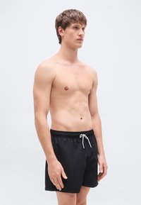 Μαύρα μαγιό με ελαστική μέση και γκρι κορδόνι. Διαθέτουν απλή, λεία υφή και καθημερινό σχεδιασμό.