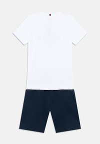 Λευκό βαμβακερό T-shirt με κοντά μανίκια και ένα ζευγάρι σορτς σε ναυτικό μπλε, με καθαρό σχέδιο και ομαλή υφή, χωρίς σχέδια ή διακοσμητικά στοιχεία.