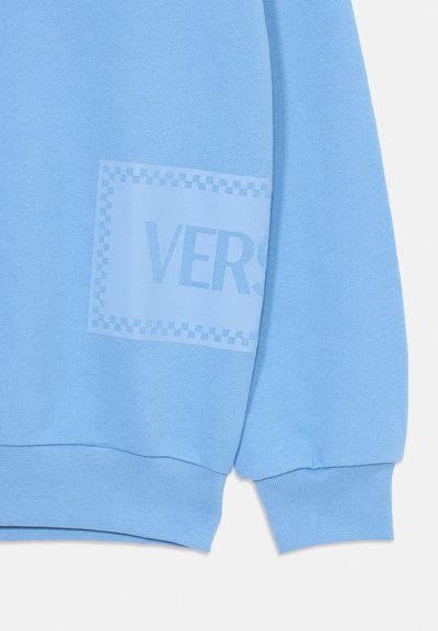 Ljusblå sweatshirt med en texturerad yta, med en tonad "VERS"-tryck inom en kantad fyrkant. Ribbad ärm- och nederkant.